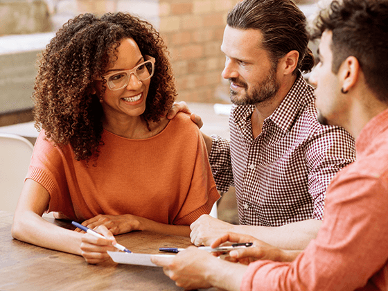 three people reviewing paperwork and smiling