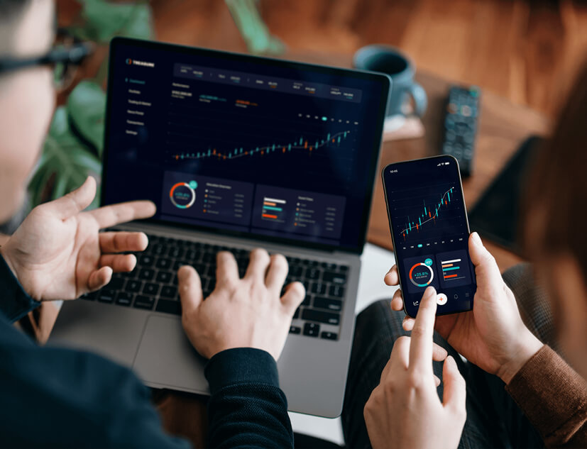 two people looking at charts on computer and phone